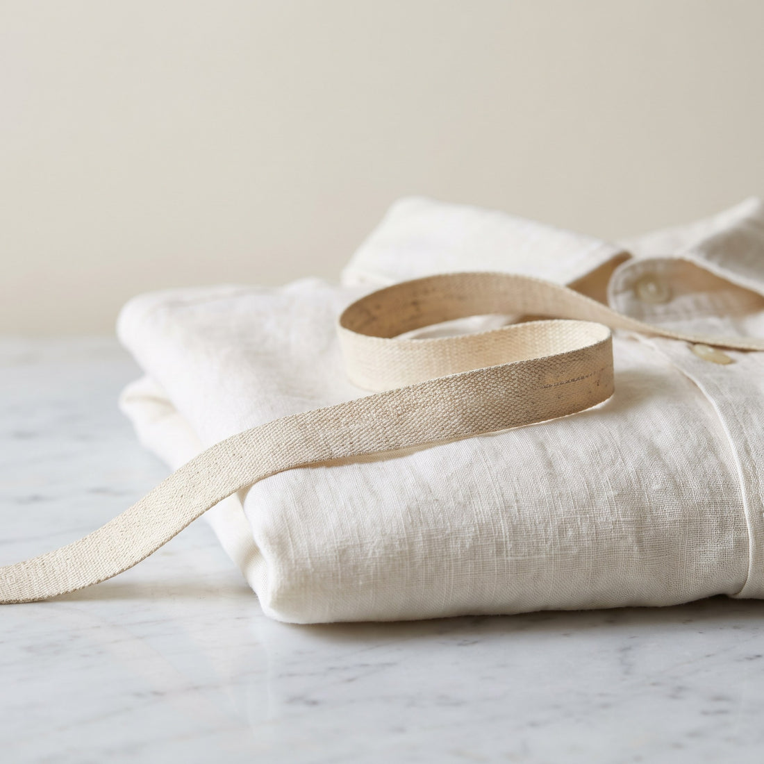 Tape measure across a folded ivory linen shirt